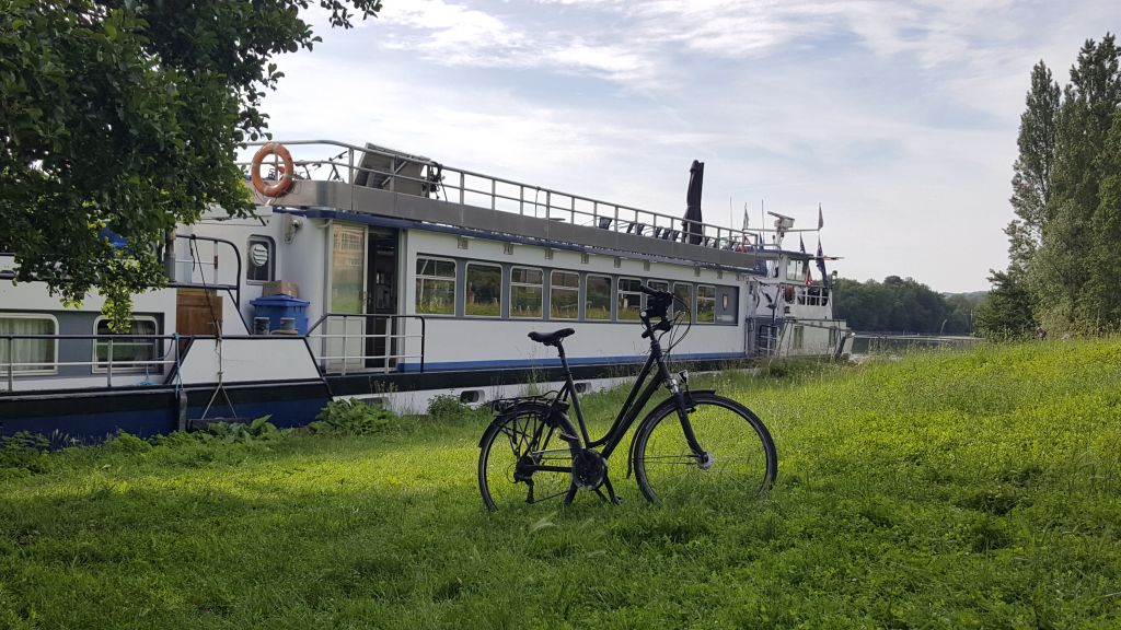 Bici parcheggiata su un prato verde con nave attraccata dietro